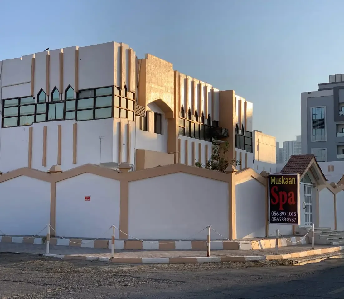 Modern white and gold spa building with geometric architecture and Muskaan Spa signage.
