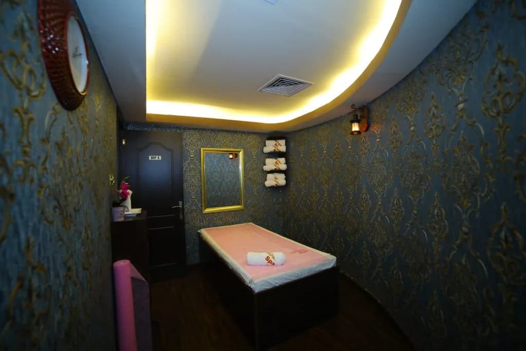 Spa treatment room with patterned walls, glowing ceiling, and massage table