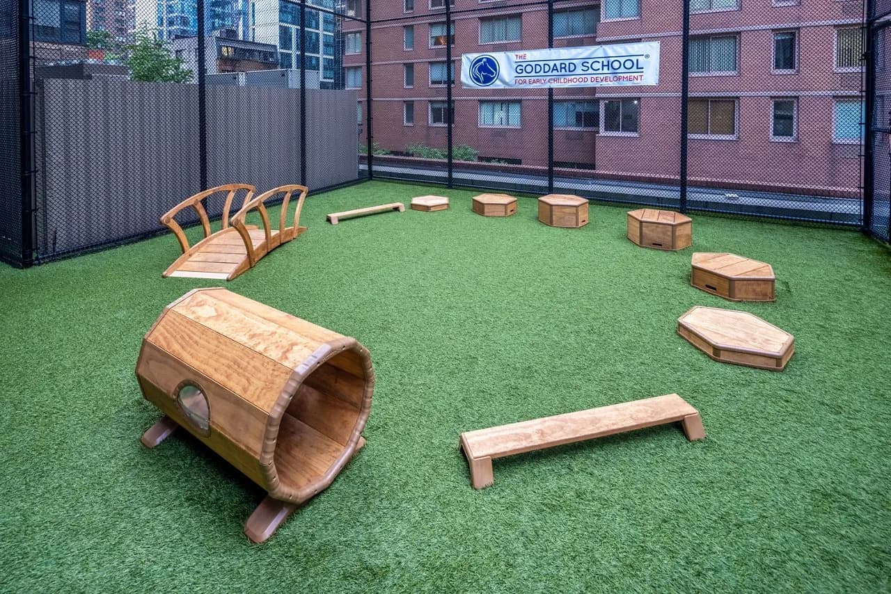 Outdoor play area with wooden play structures and equipment on green turf