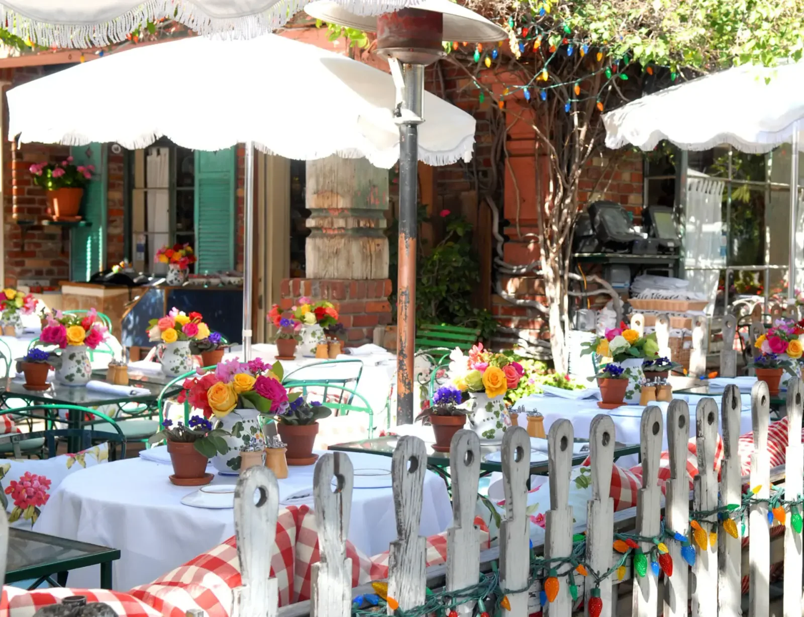 Sunny outdoor patio with flower arrangements, white umbrellas, and festive decorations