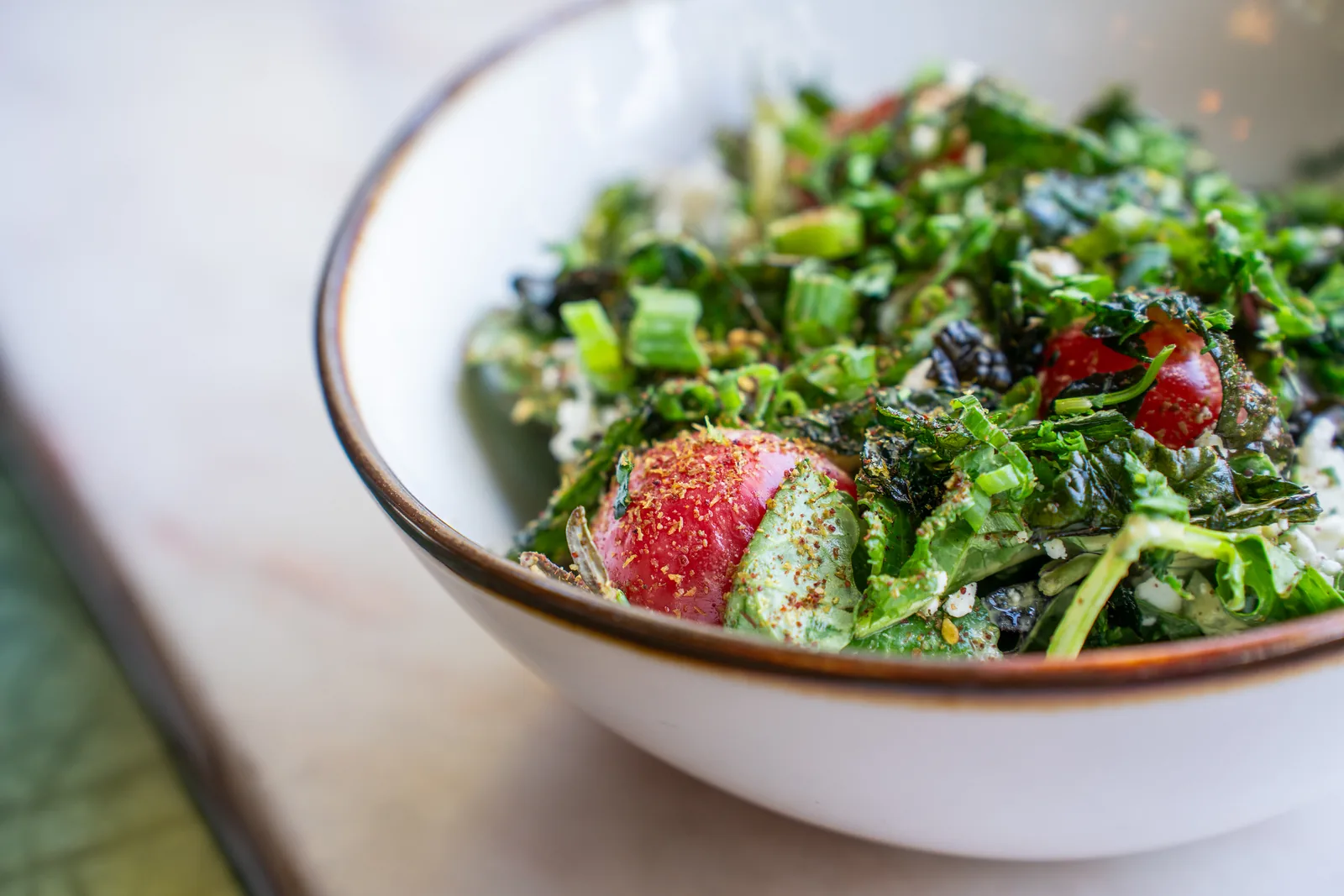 Fresh green salad with radishes and herbs in a white bowl with bronze rim