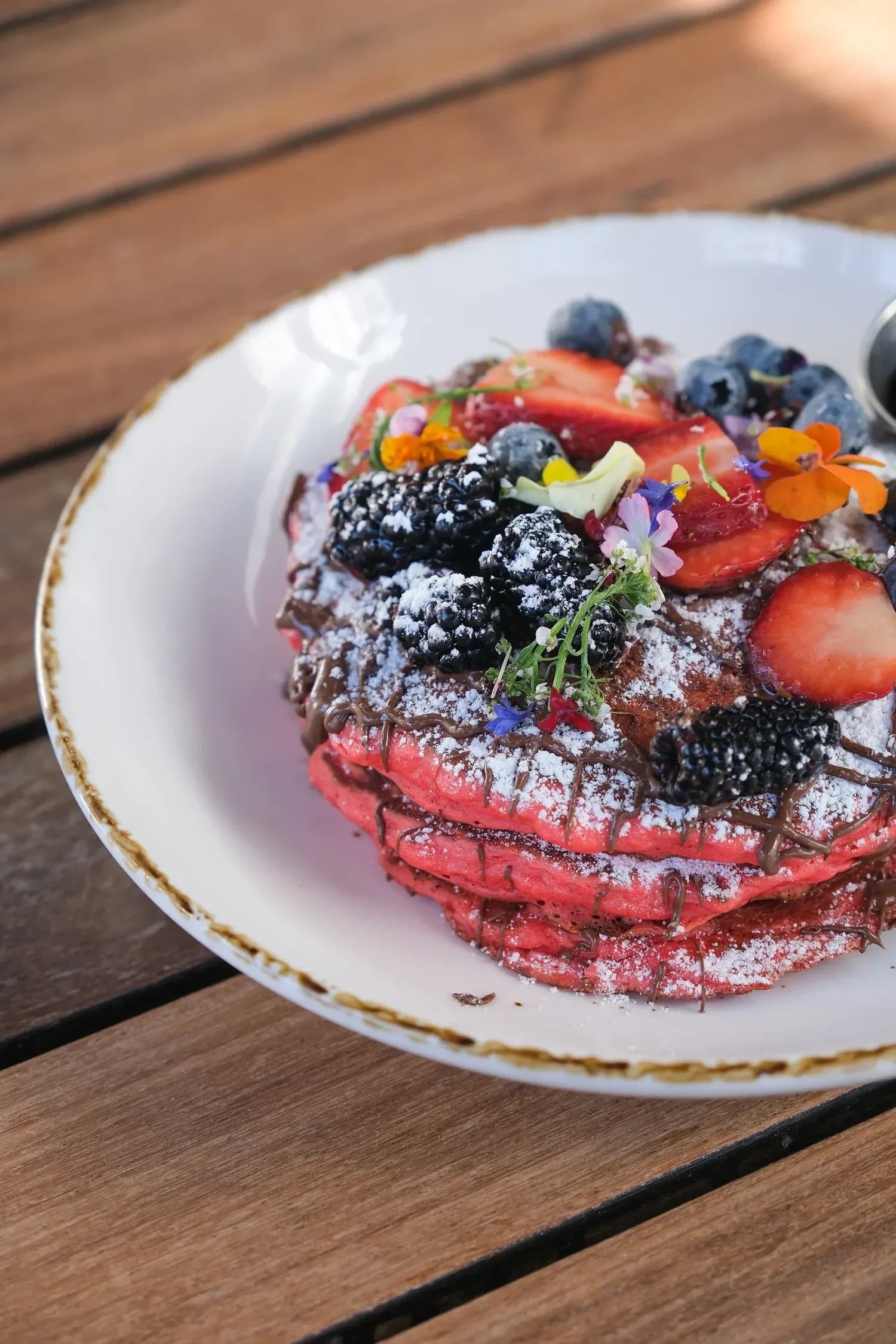 Gourmet berry meringue dessert with blackberries, strawberries, blueberries and edible flowers on a white plate