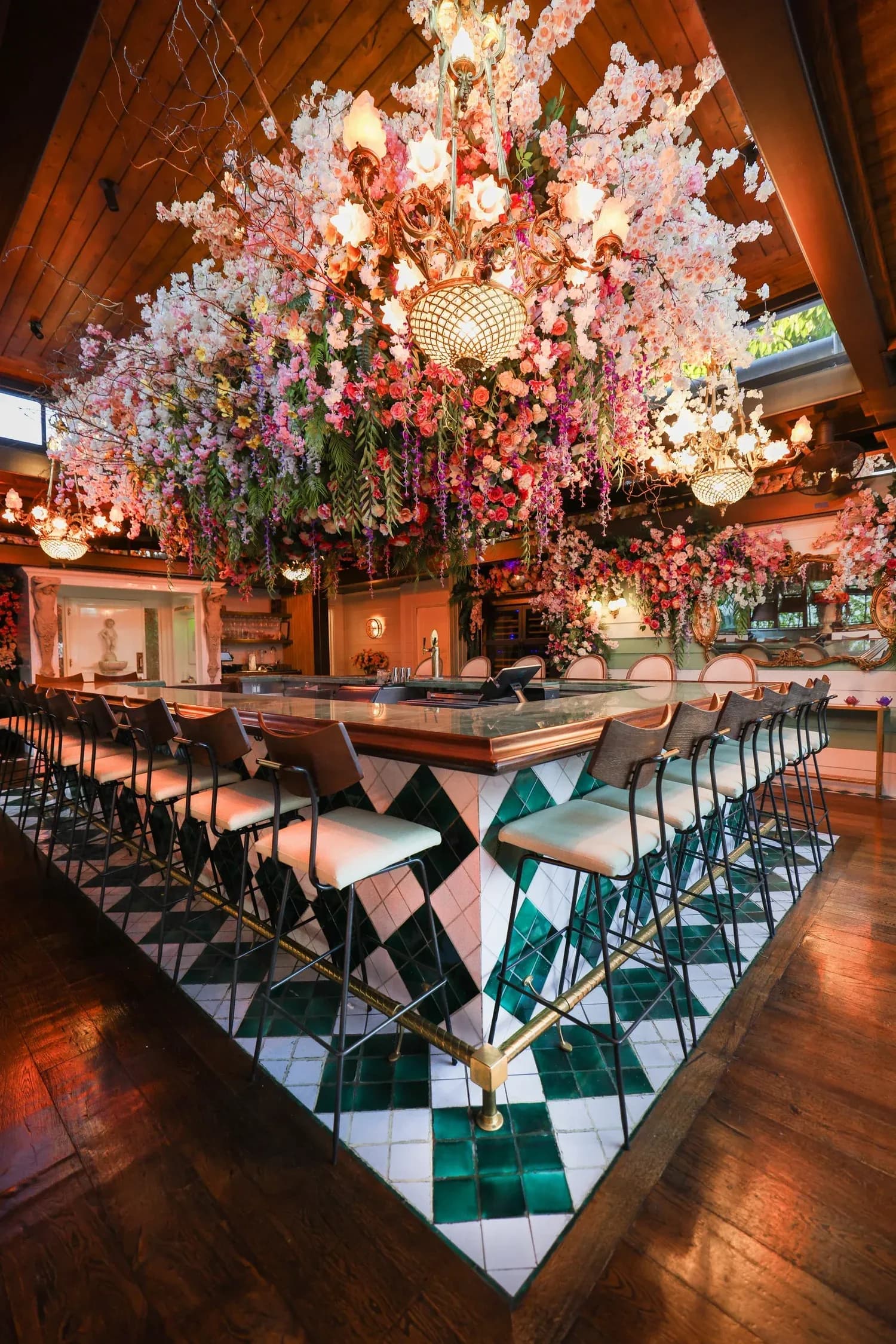 Restaurant bar with dramatic pink and white hanging floral installation and geometric floor pattern