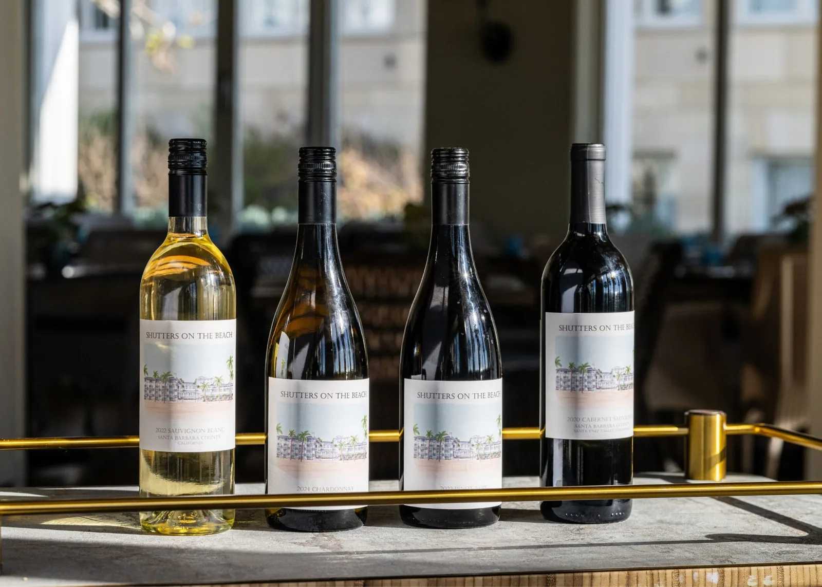 Four bottles of Shutters on the Beach wine on display at a restaurant counter