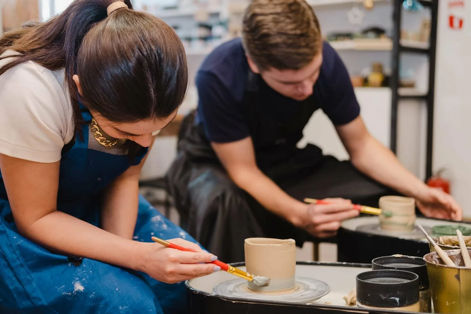 Students working on pottery with clay at a studio workspace