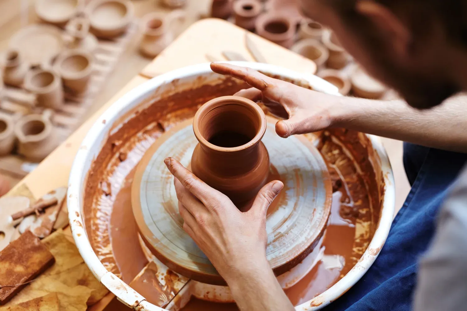 Potter's hands shaping wet clay on a spinning pottery wheel