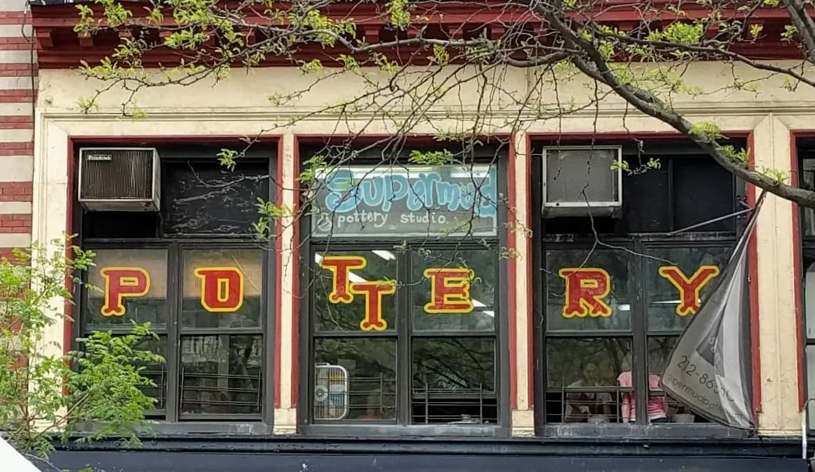 Supermud Pottery storefront with yellow letter signage on dark window frames