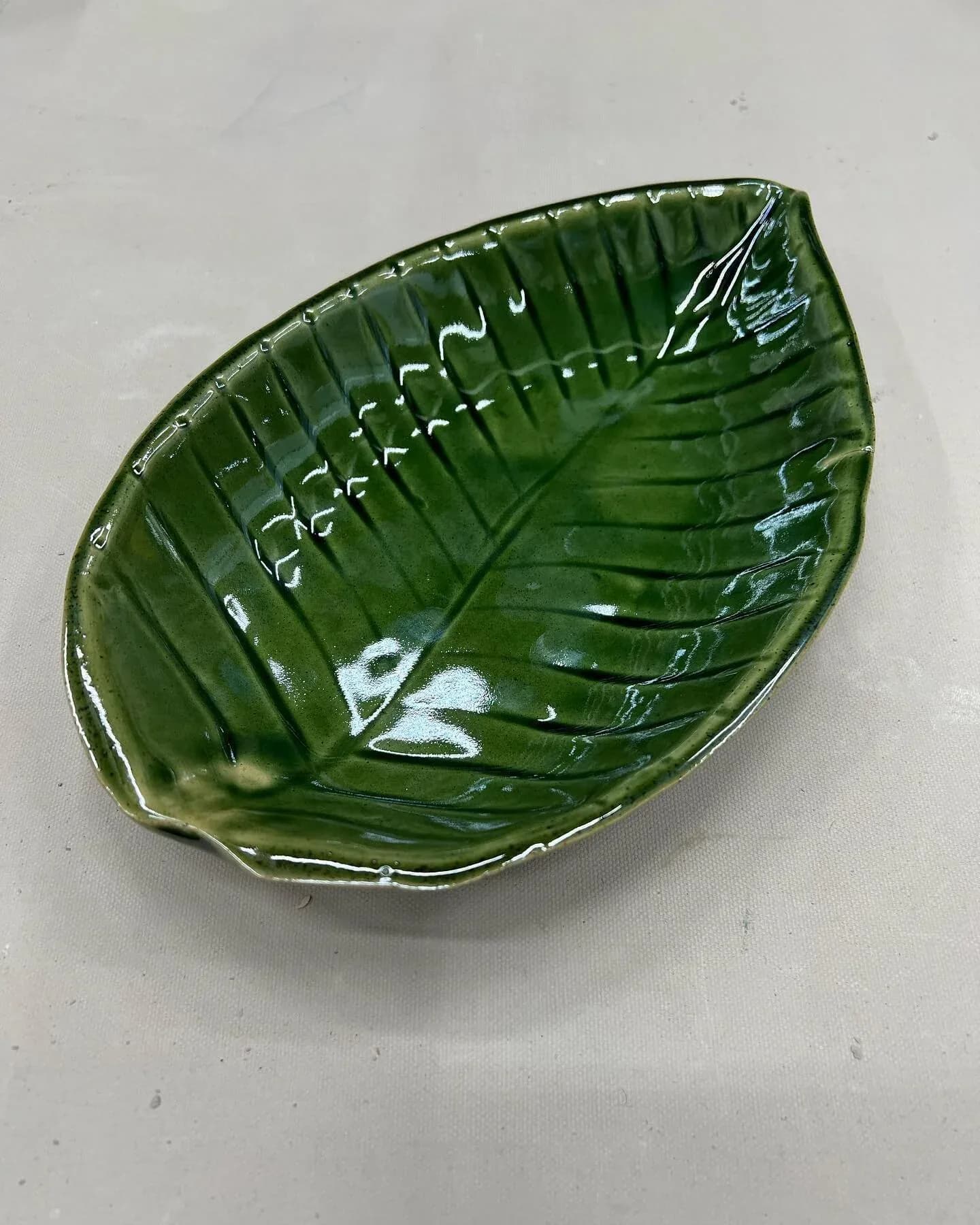 Green ceramic leaf-shaped dish with veined texture and glossy glaze