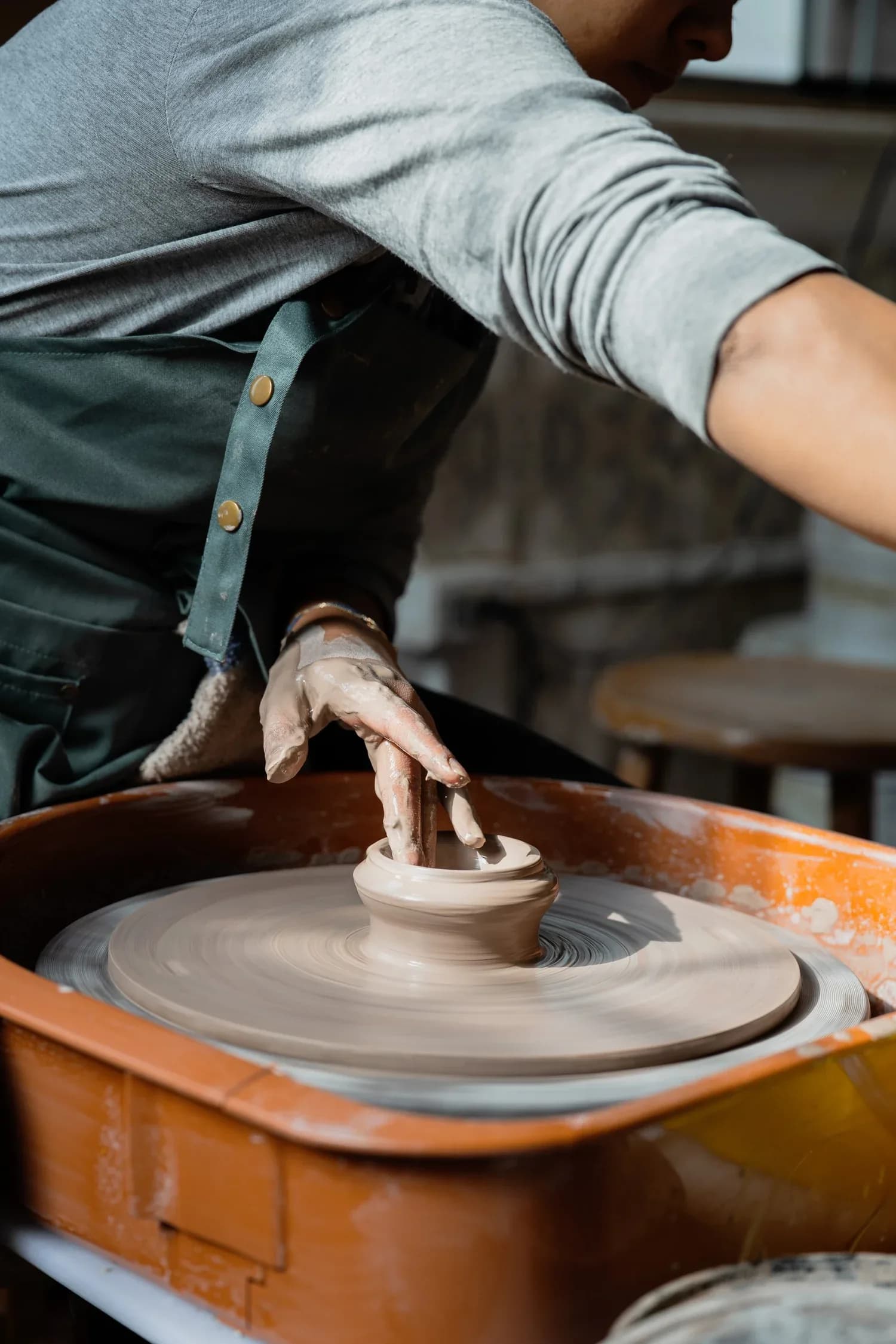 Potter shaping clay on a spinning wheel in studio