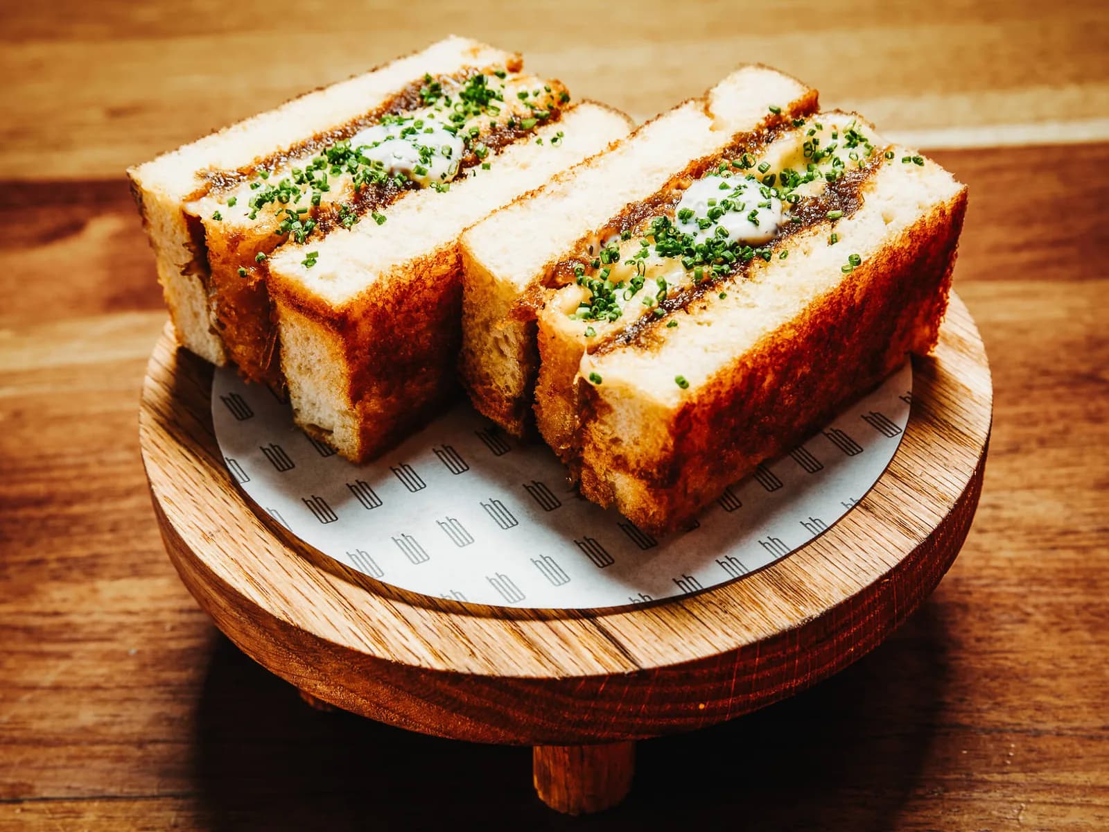 Four slices of topped toast with herbs on a wooden serving board