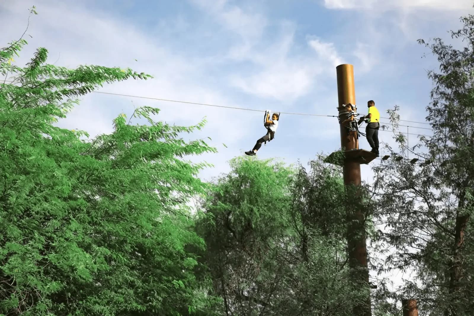Person ziplining between tall wooden poles at an adventure park