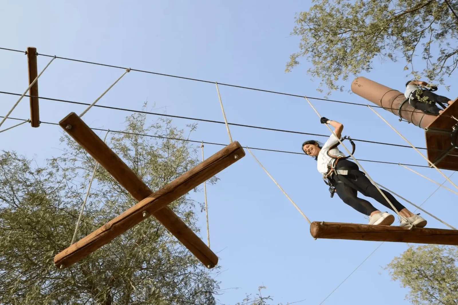 Person on adventure park course crossing wooden beams high above ground