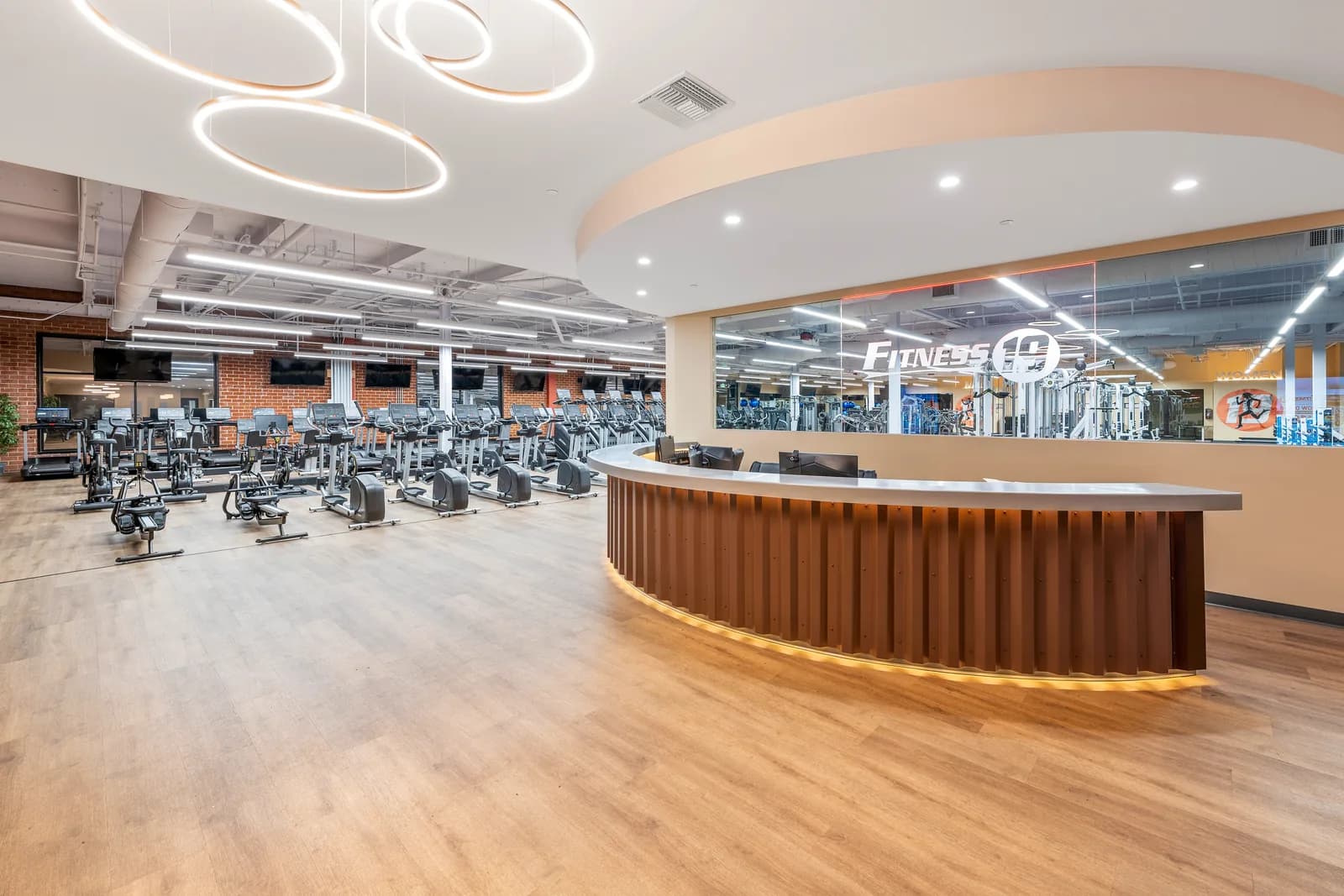 Bright, modern gym reception area with cardio equipment visible in the background