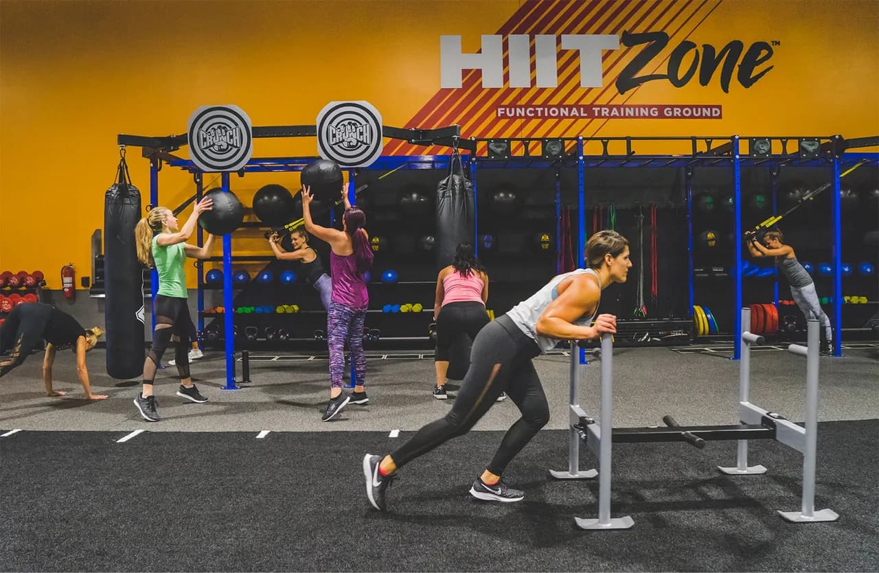 Group fitness class with members doing functional training exercises in a modern gym facility