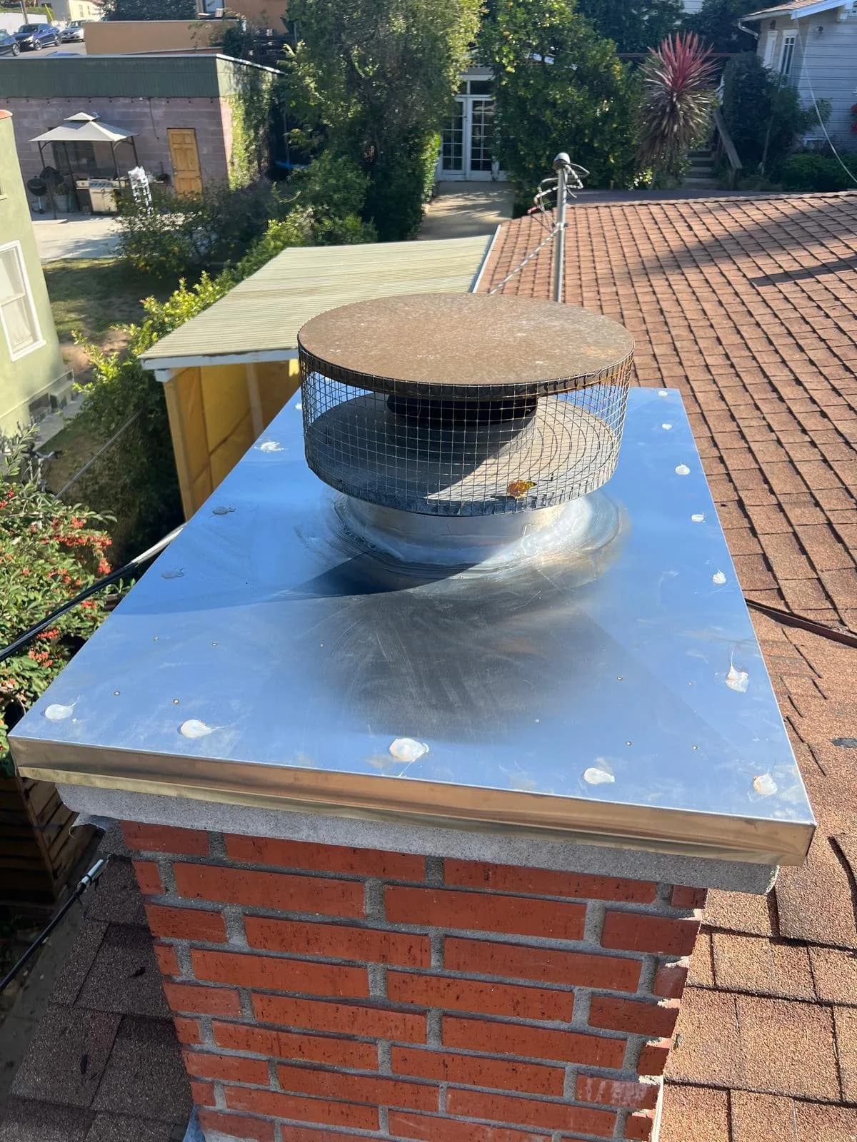 Installed chimney cap with rain cover and mesh screening on brick chimney