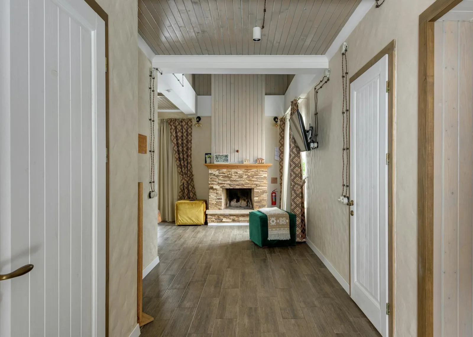 Hallway with fireplace display, wood floors, white doors, stone chimney surround, and product samples