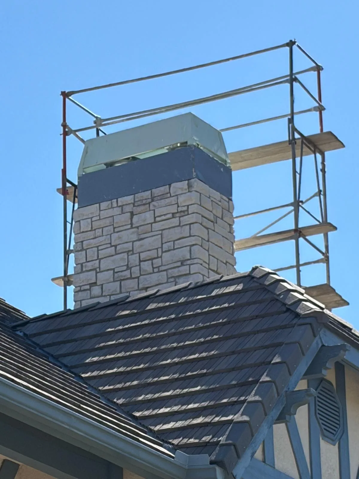 Brick chimney under construction with metal scaffolding and protective covering