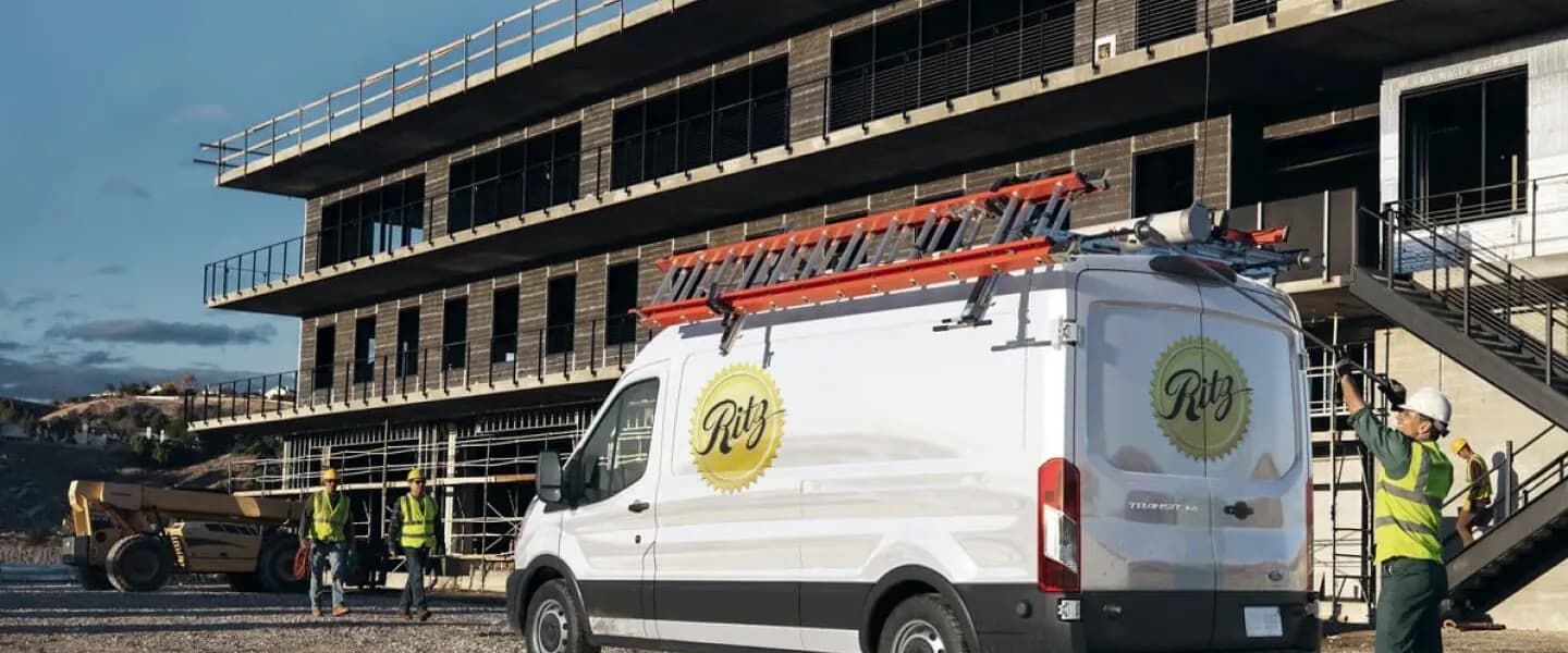 Ritz Plumbing service van and workers at a large commercial construction site