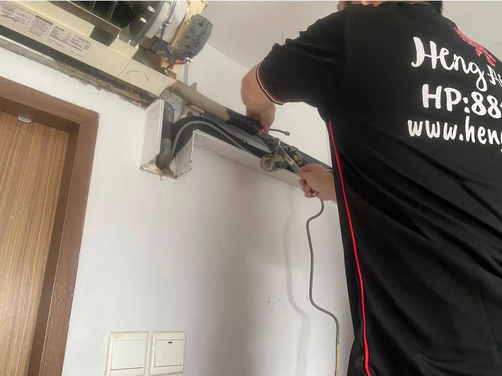 Technician servicing an air conditioning unit indoors
