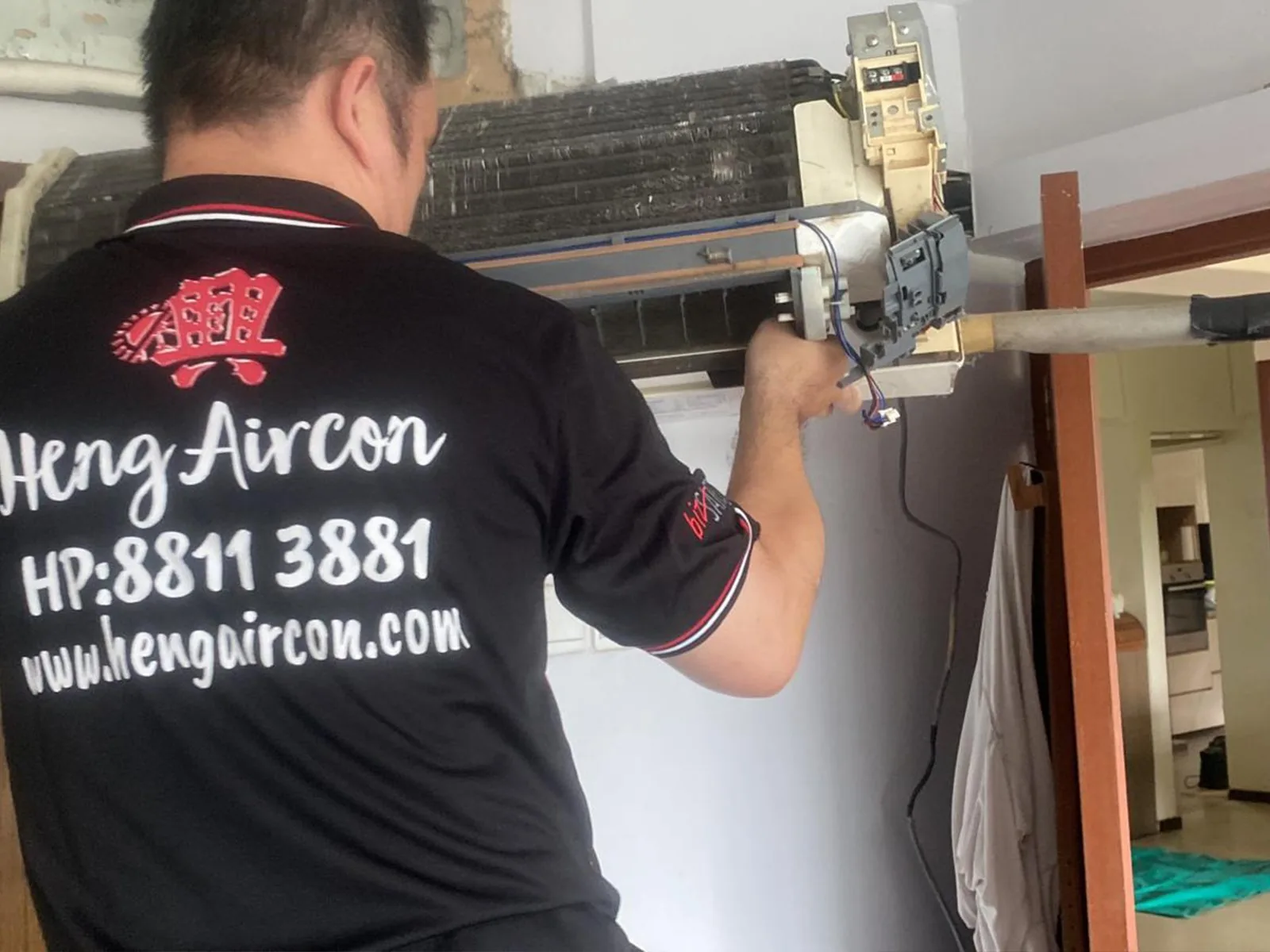 Heng Aircon technician servicing an air conditioning unit indoors