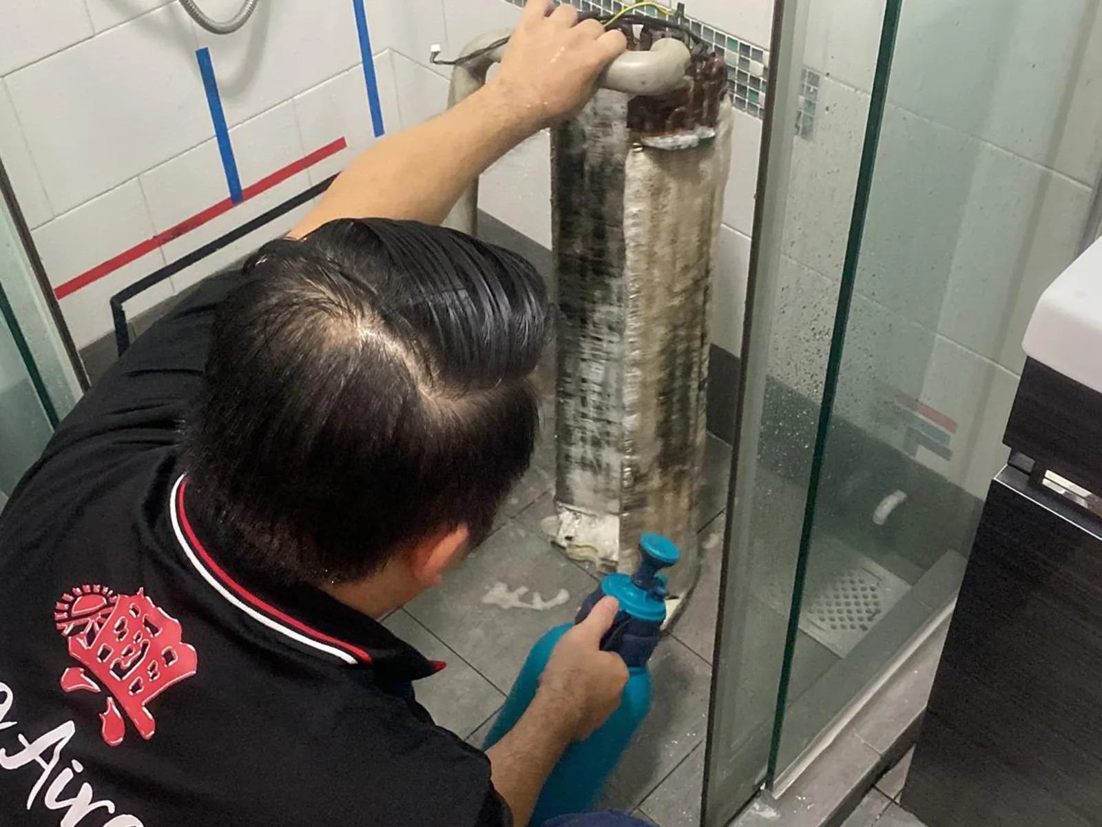 Technician servicing an indoor air conditioning unit with cleaning tools