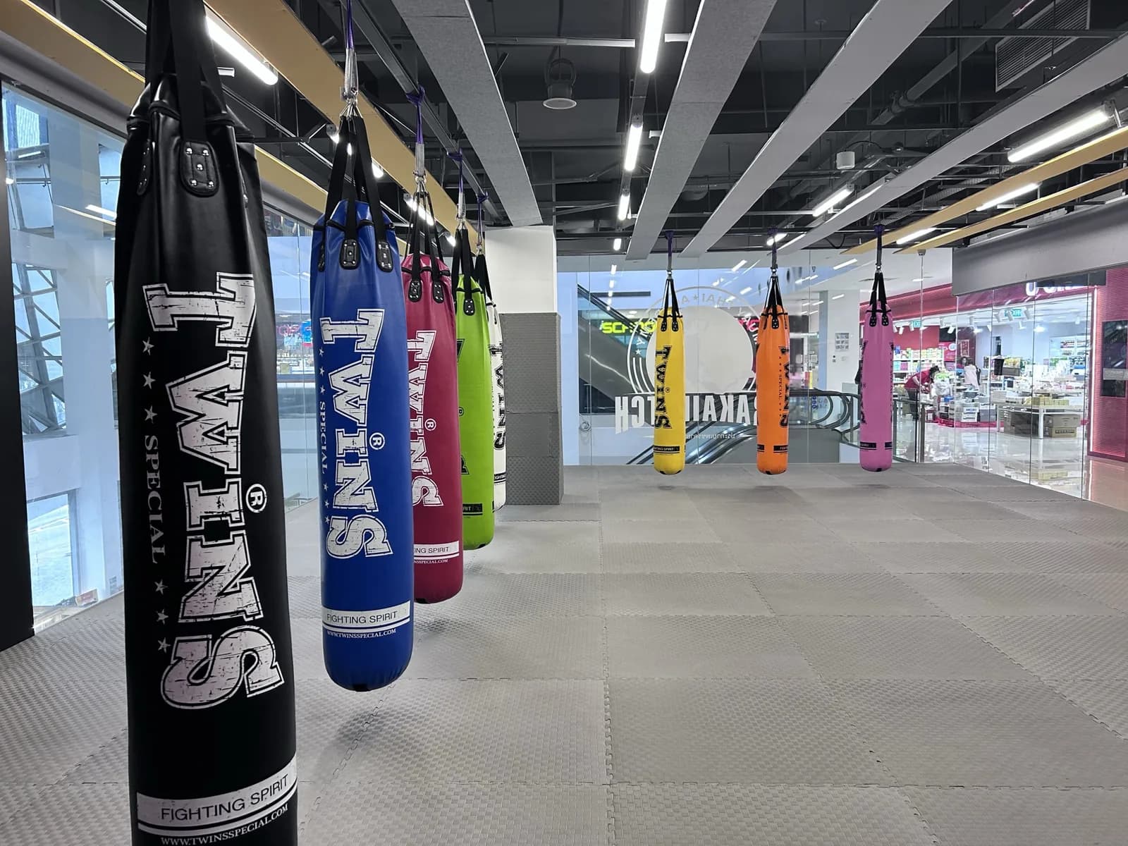 Muay Thai gym training area with hanging heavy bags in various colors