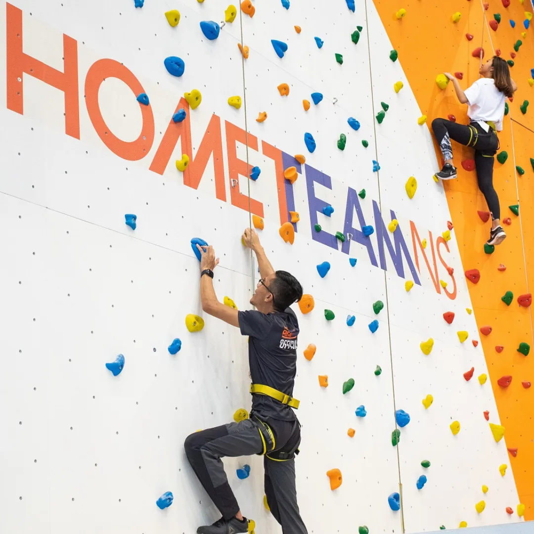 Climbers on indoor rock walls with colorful holds at Adventure HQ