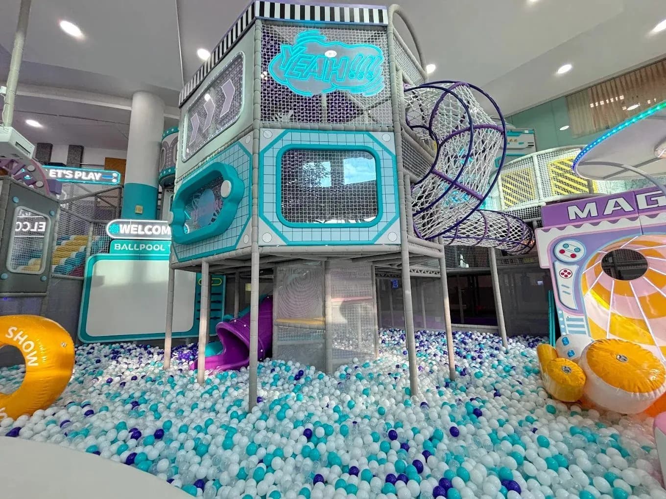 Multi-level turquoise and purple play structure in a ball pool at an indoor playground