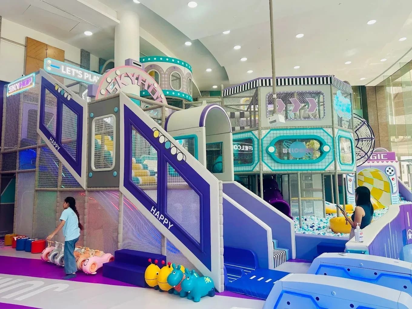 Multi-level indoor playground with slides, climbing structures, and ball pits in bright colors.