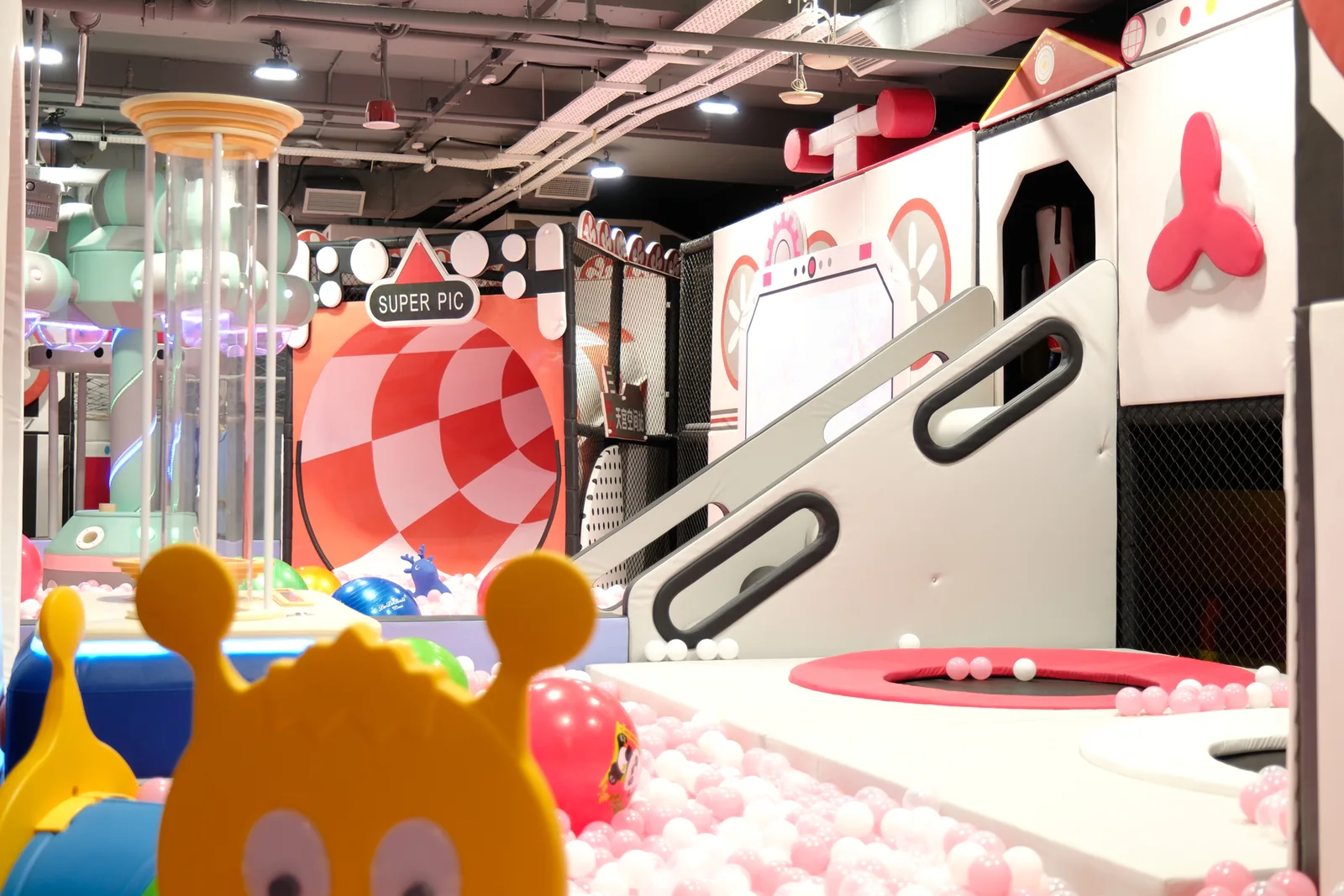 Colorful indoor play area with red and white game machines, ball pit, and bright lighting