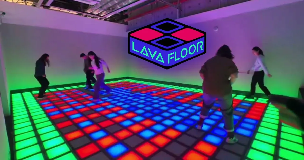 Visitors dancing on an illuminated LED floor with multicolored tiles and Lava Floor neon sign overhead