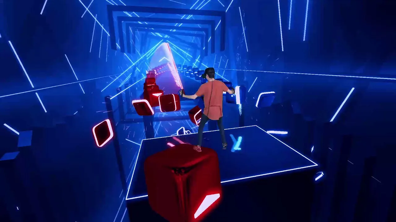 Person in orange shirt using VR equipment in a neon-lit digital environment with red and blue glowing shapes