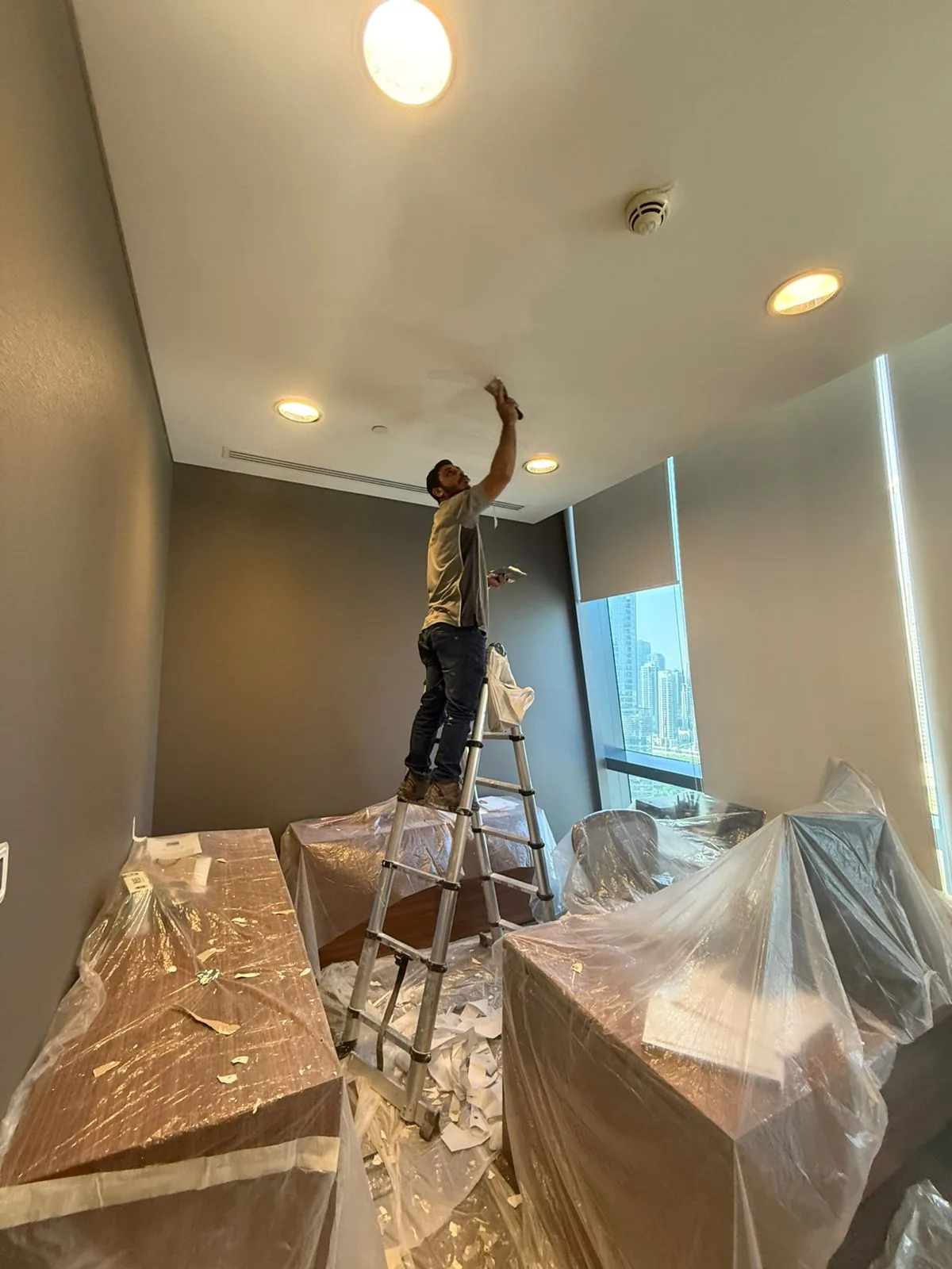 Technician on ladder working on ceiling in protected indoor space