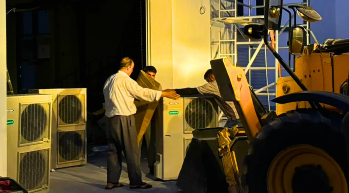 Technicians servicing air conditioning units and equipment during evening maintenance work