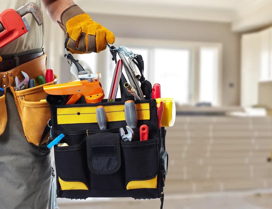 Worker in work gloves holding tool belt with hand tools in residential interior