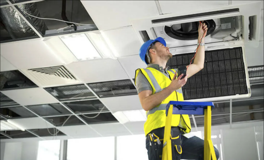 Technician servicing ceiling-mounted air conditioning unit