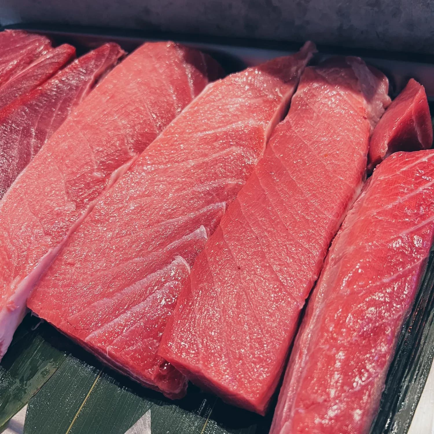 Fresh red tuna or salmon steaks arranged on a dark serving tray