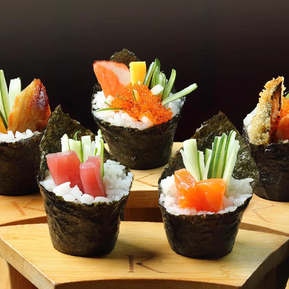 Colorful hand rolls with salmon, roe, and vegetables on wooden serving board