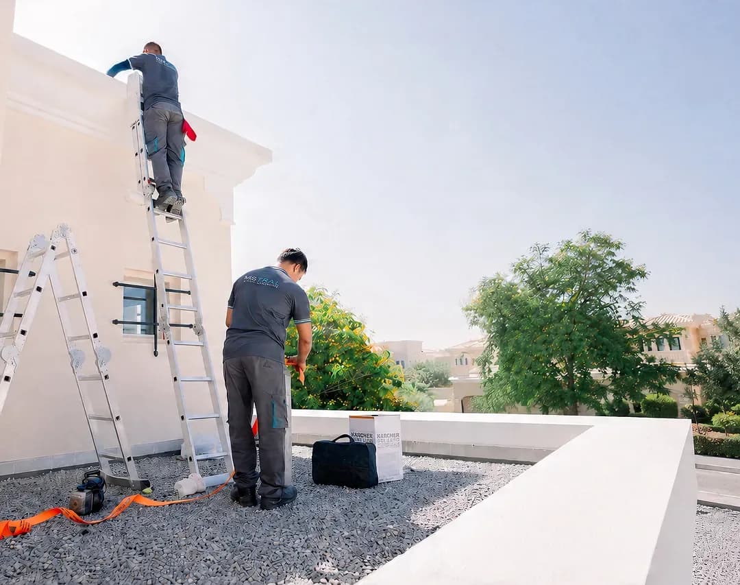 Technicians performing building maintenance on exterior facade with ladder
