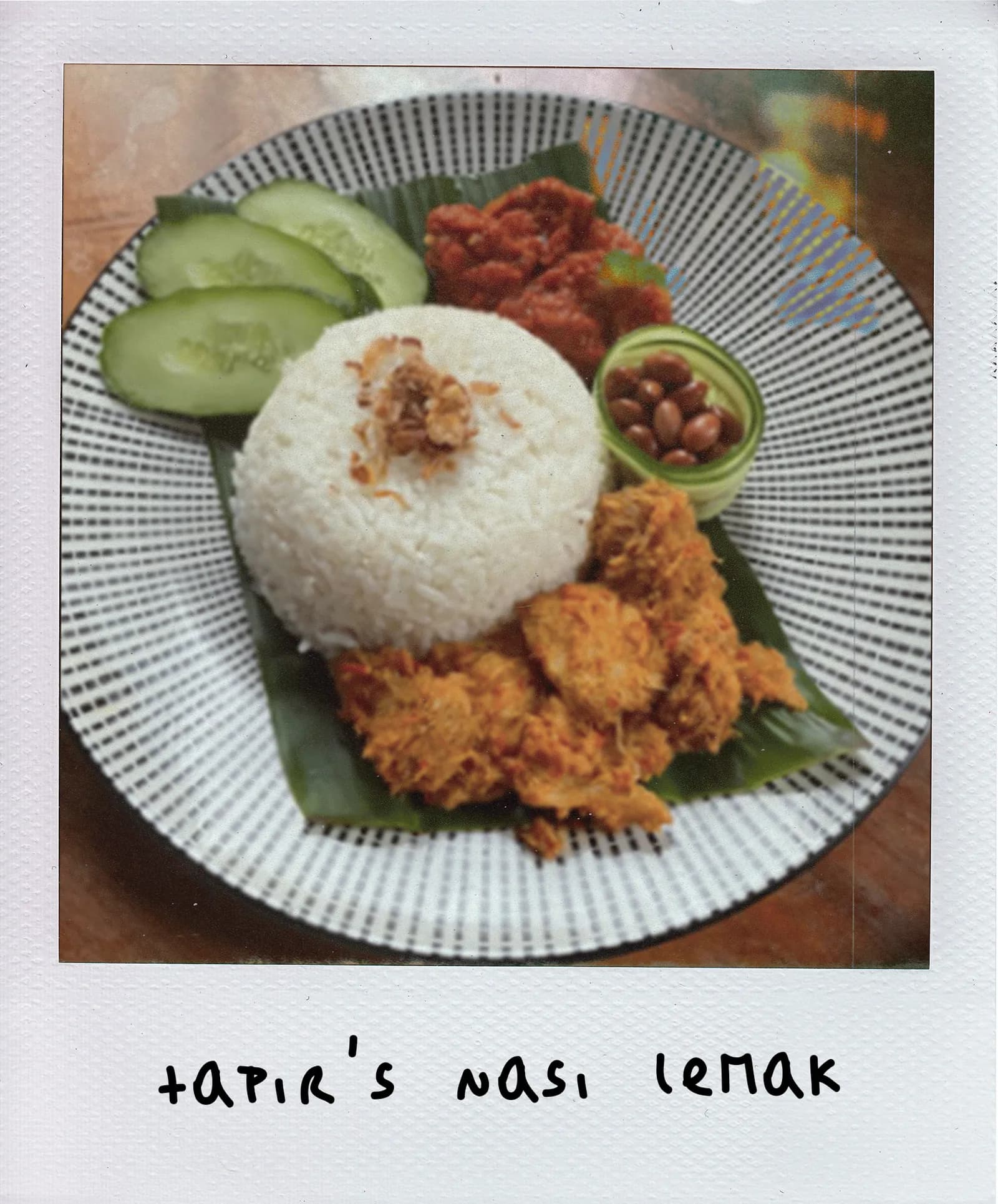 Nasi lemak plate with coconut rice, fried chicken, cucumber, sambal, and peanuts